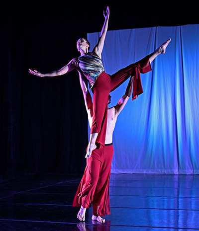 a man lifts a woman in a dance, both wearing red