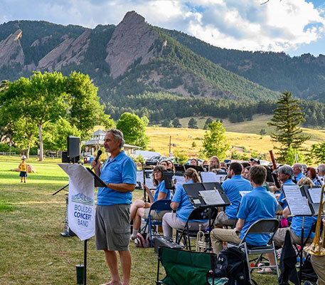 Boulder Concert Band performing outside in a park with mountains in the background