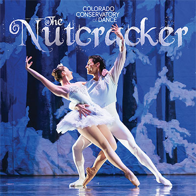 A male and female ballerina, wearing white, dancing together on a stage lit with blue. The title "The Nutcracker" is displayed behind them in curving letters